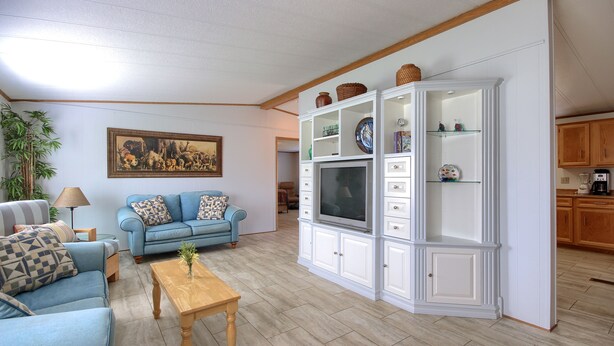 A living room with a blue sofa, a wooden coffee table, a TV stand, and a painting on the wall. - Bear Creek Ranch in tranquil setting near Yosemite Valley/Merced River (Catheys Valley)