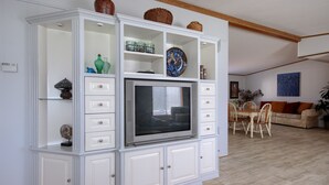 A living room with a white entertainment center, a flat-screen TV, and a dining area with a wooden table and chairs. - Bear Creek Ranch in tranquil setting near Yosemite Valley/Merced River (Catheys Valley)