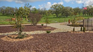 A landscaped park area with a gravel path, trees, and a wooden fence. - Bear Creek Ranch in tranquil setting near Yosemite Valley/Merced River (Catheys Valley)