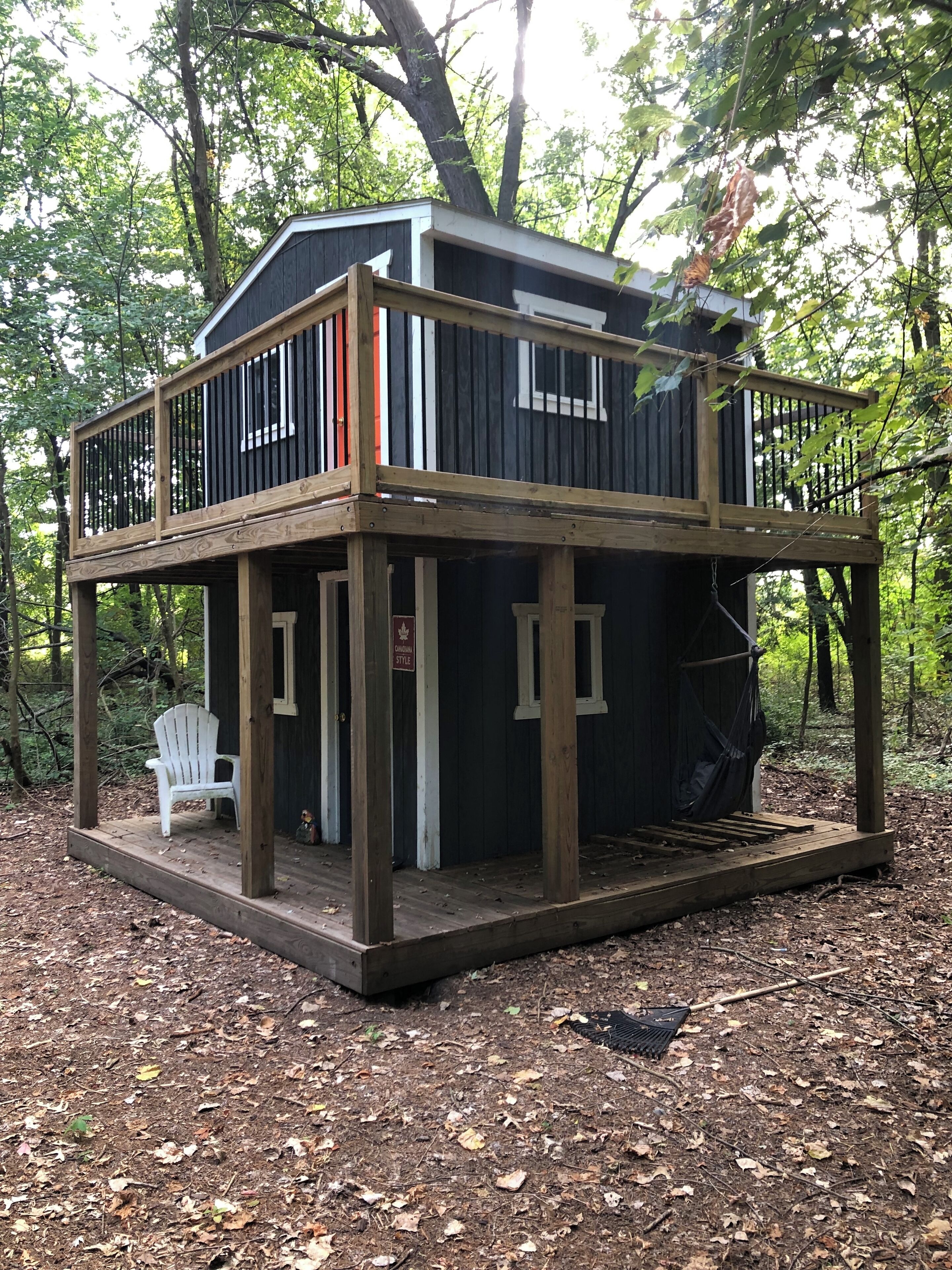 A cabin with a wooden deck, a white chair, and a hammock.