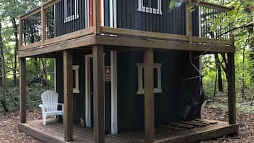 A cabin with a wooden deck, a white chair, and a hammock.