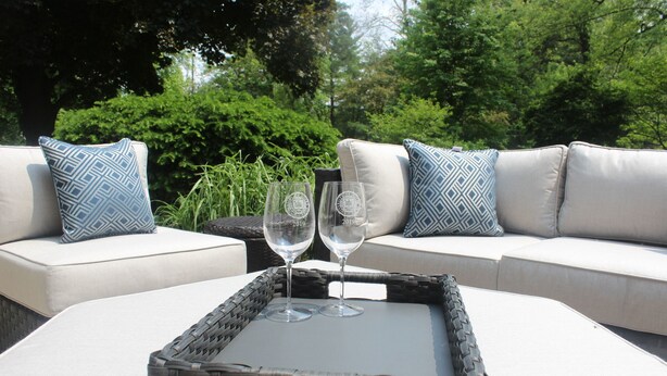 A wicker tray with two wine glasses on a white table, set on a beige sofa with patterned cushions. - FOOTBALL WEEKEND GET-A-WAY - with outdoor space to die for. (South Bend)