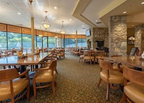 Enjoy meals in this dining area with high ceilings and large windows, a stone fireplace, and a television for your convenience.