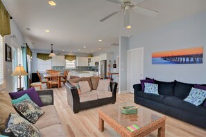 A spacious living area with a dining table, two sofas, a coffee table, and a kitchen in the background.
