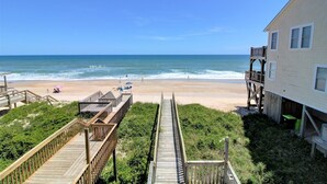 A beach view from a wooden deck with a house on the right. - Surf Monkeys: A stunning 5-bedroom oceanfront home in Surf City, NC. (Surf City)
