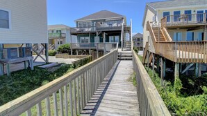 A wooden boardwalk connecting two beachfront properties with balconies and outdoor access. - Surf Monkeys: A stunning 5-bedroom oceanfront home in Surf City, NC. (Surf City)