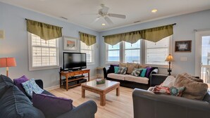 A living room with a television, two sofas, a coffee table, and a ceiling fan. - Surf Monkeys: A stunning 5-bedroom oceanfront home in Surf City, NC. (Surf City)