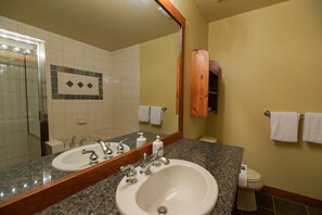 Et badeværelse med to håndvaske, et spejl og et toilet.