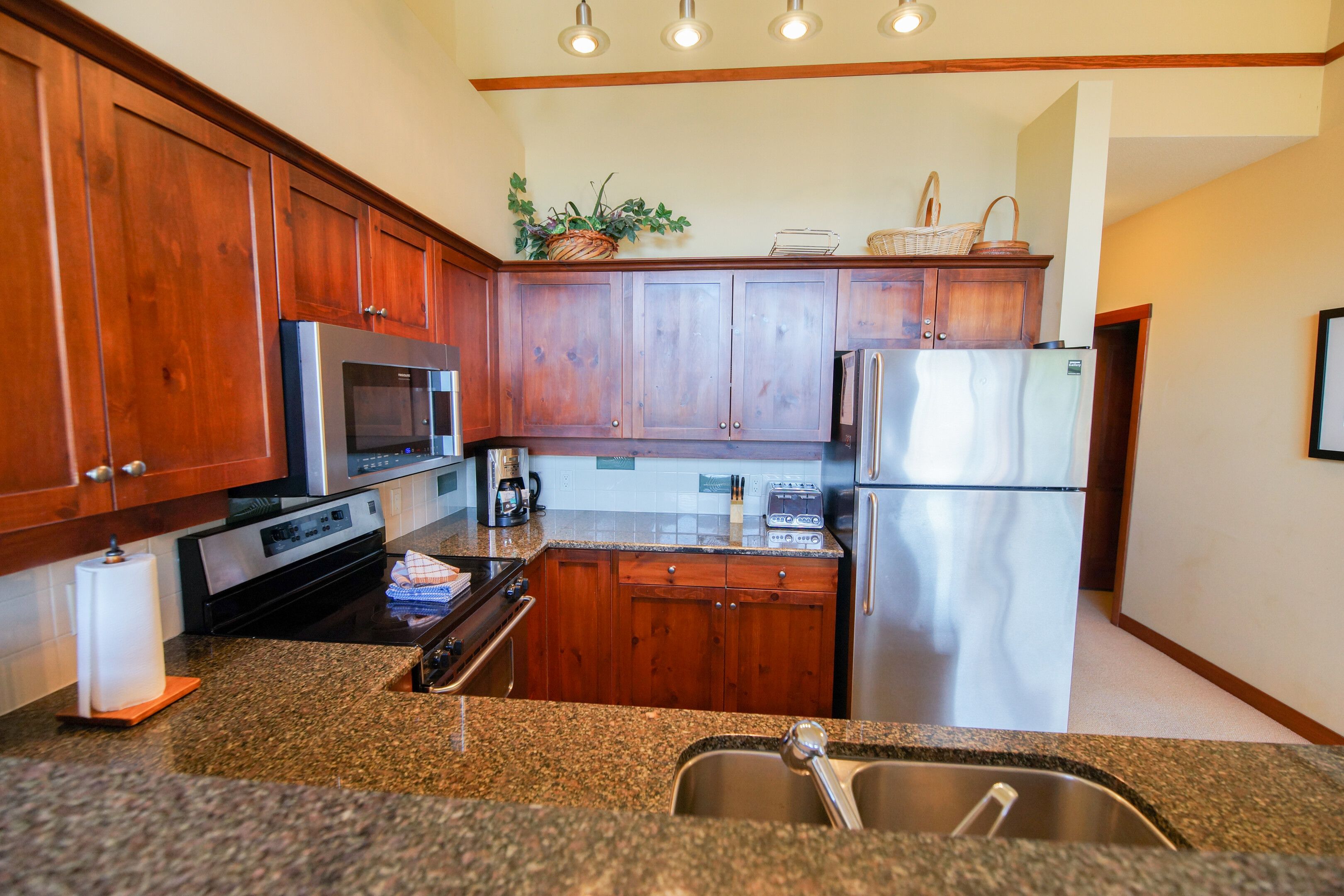 A kitchen with wooden cabinets, stainless steel appliances, granite countertops, and a built-in sink.
