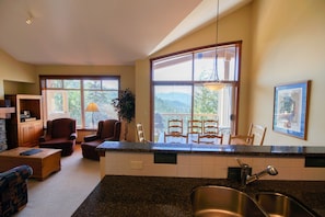 A kitchen with a granite countertop, a stainless steel sink, and a dining area with a table and chairs. - Taluswood - The Bluffs 3 (Whistler)
