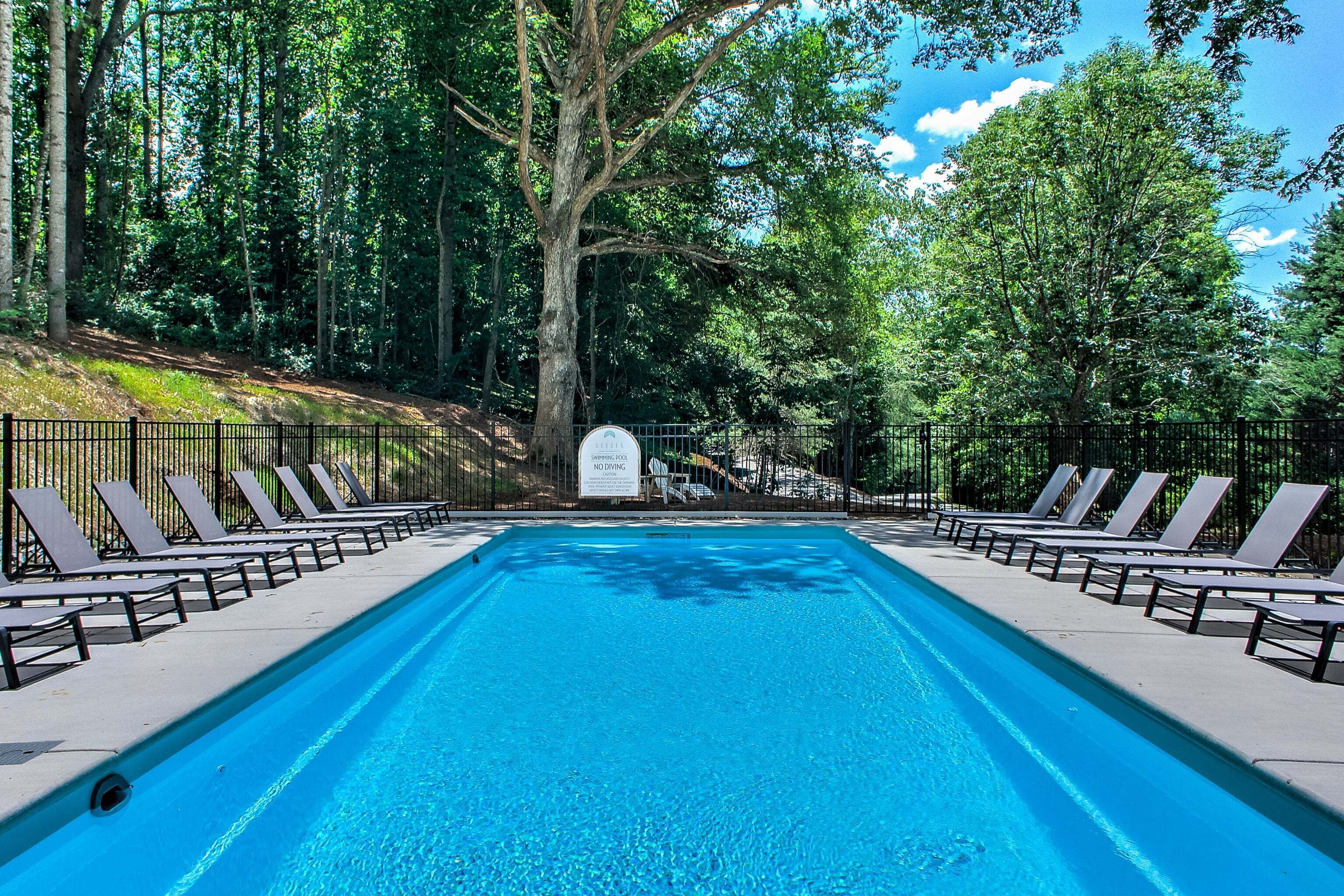 A swimming pool with lounge chairs and a sign indicating no diving.