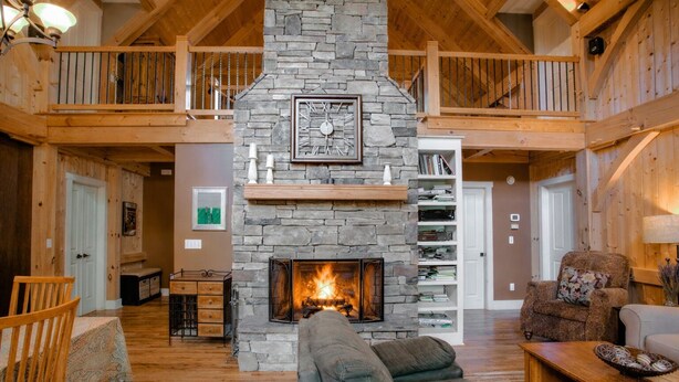 A spacious living room with a stone fireplace, wooden beams, and a cozy seating area.