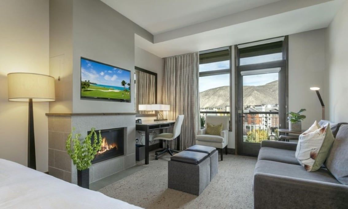 Relax in the bright studio living area with a fireplace, TV, sofa, and mountain views.