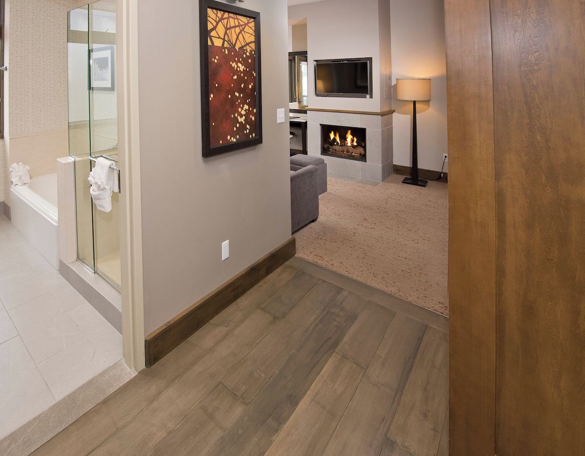 A hallway with a fireplace, a TV mounted on the wall, and a glass shower enclosure.