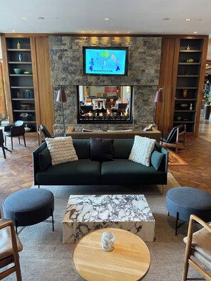 A modern living room with a fireplace, a television mounted above it, and a seating area with a sofa and chairs. - Charlie Rentz: Riverfront Resort/Spa, Ski-In/Out, Hot Tubs, Private Balcony, Room Service #820 (Avon)