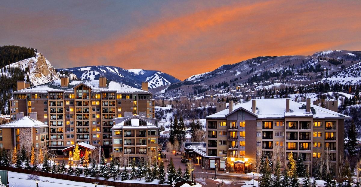 A hotel with multiple buildings, a snow-covered landscape, and mountains in the background.