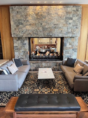 A living room with a stone fireplace, two sofas, a coffee table, and a patterned rug. - Resort/Spa, Ski in/out, Hot Tub, 8th Fl, RmService (Avon)