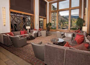A spacious lobby with multiple seating areas, large windows offering a mountain view, and a decorative wall with a geometric pattern.