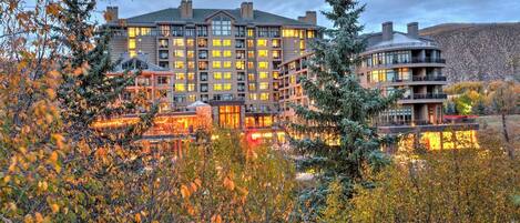A multi-story hotel with a central courtyard, surrounded by trees and a mountainous backdrop.