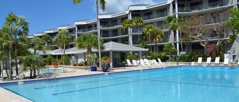 Un hôtel doté d’une piscine, de palmiers et de nombreux balcons.