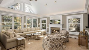 Un salon spacieux avec un grand canapé d’angle, deux fauteuils et une cheminée.