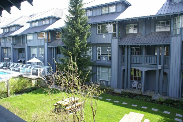 A multi-story building with a pool area, outdoor seating, and a well-maintained lawn.