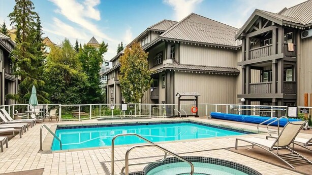 A swimming pool with a hot tub, lounge chairs, and a fenced deck area. - Glacier Lodge - Deluxe Ski in/Ski out (Whistler)