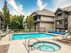 Ein Swimmingpool mit Whirlpool, Liegestühlen und einem eingezäunten Deckbereich.