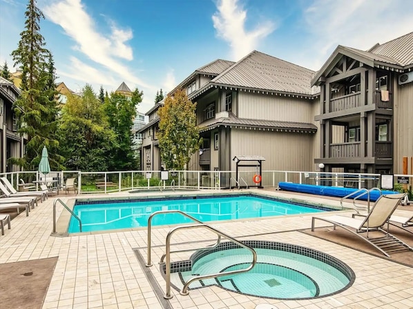 Ein Swimmingpool mit Whirlpool, Liegestühlen und einem eingezäunten Deckbereich.