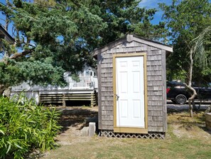A small wooden shed with a white door, surrounded by greenery and a white fence. - Isle Of Skye: Sandy sound side beach, excellent for water activities. (Ocracoke)