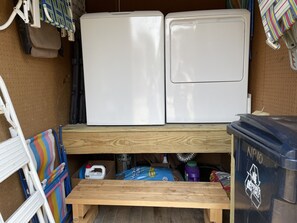 A compact storage area with two white refrigerators, a wooden bench, and a recycling bin. - Isle Of Skye: Sandy sound side beach, excellent for water activities. (Ocracoke)