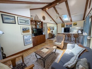A spacious living area with a television, seating, a kitchen area, and a dining space. - Isle Of Skye: Sandy sound side beach, excellent for water activities. (Ocracoke)