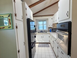 A kitchen with white cabinets, a black refrigerator, a microwave, and an oven.