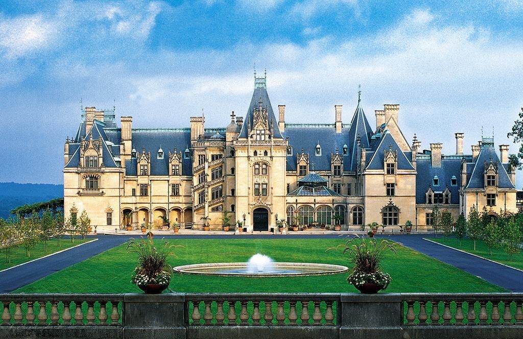 Un grand bâtiment historique à la façade symétrique, doté de nombreuses cheminées et d’une entrée centrale.
