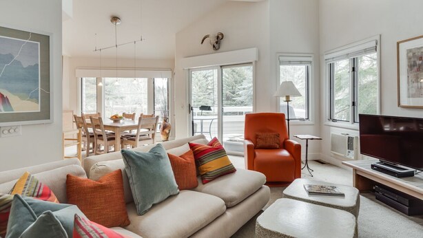 A spacious living room with a sofa, armchair, and television. - Ski Storage, Garage and Free Shuttle (Warm Springs)