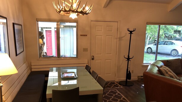 A dining area with a glass-top table, benches, a coat rack, and a view of the outside. - Iconic Sun Valley - Parkside Village - Sleeps 7 very comfortably  (Ketchum)
