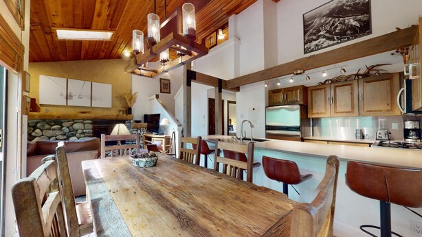 Une cuisine spacieuse avec des meubles en bois, un grand îlot central doté de tabourets et une cheminée en pierre.
