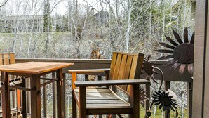 Une terrasse en bois avec une table et des chaises, entourée de sculptures en métal.