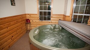 En træhytte med jacuzzi, et vindue og et lille bord med røde kopper.