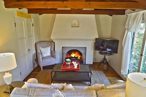 A cozy living room with a fireplace, a sofa, a coffee table with decorative items, and a television.