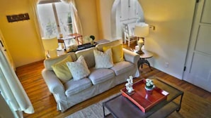 Un salon avec un canapé, une table basse, une lampe et une fenêtre avec des rideaux.