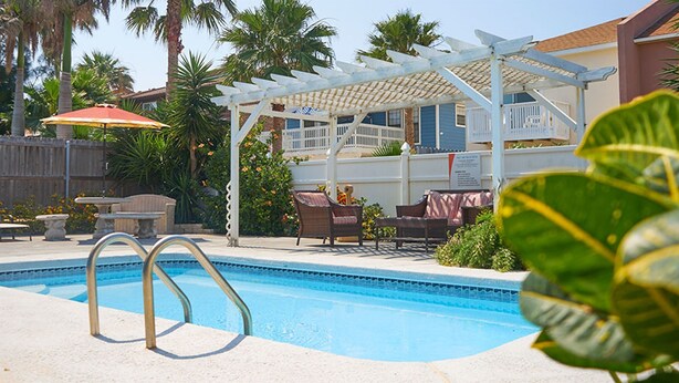 Una piscina con una pérgola y mobiliario exterior.