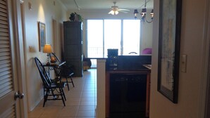 A hallway with a dining area, kitchen, and a door leading to another room. - Inn at Dauphin Island 211 Beautiful Views!! (Dauphin Island)