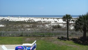 A beach view with a fenced area, a palm tree, and a lounge chair. - Inn at Dauphin Island 211 Beautiful Views!! (Dauphin Island)