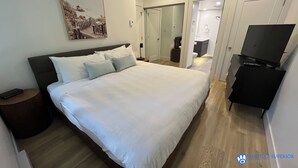 Een hotelkamer met een groot bed, een televisie en een schilderij aan de muur.