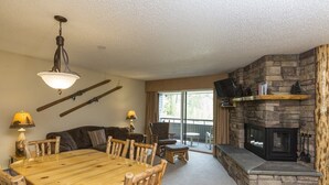 Ein Essbereich mit Holztisch und -stühlen, einem Kamin und einer Steinwand.