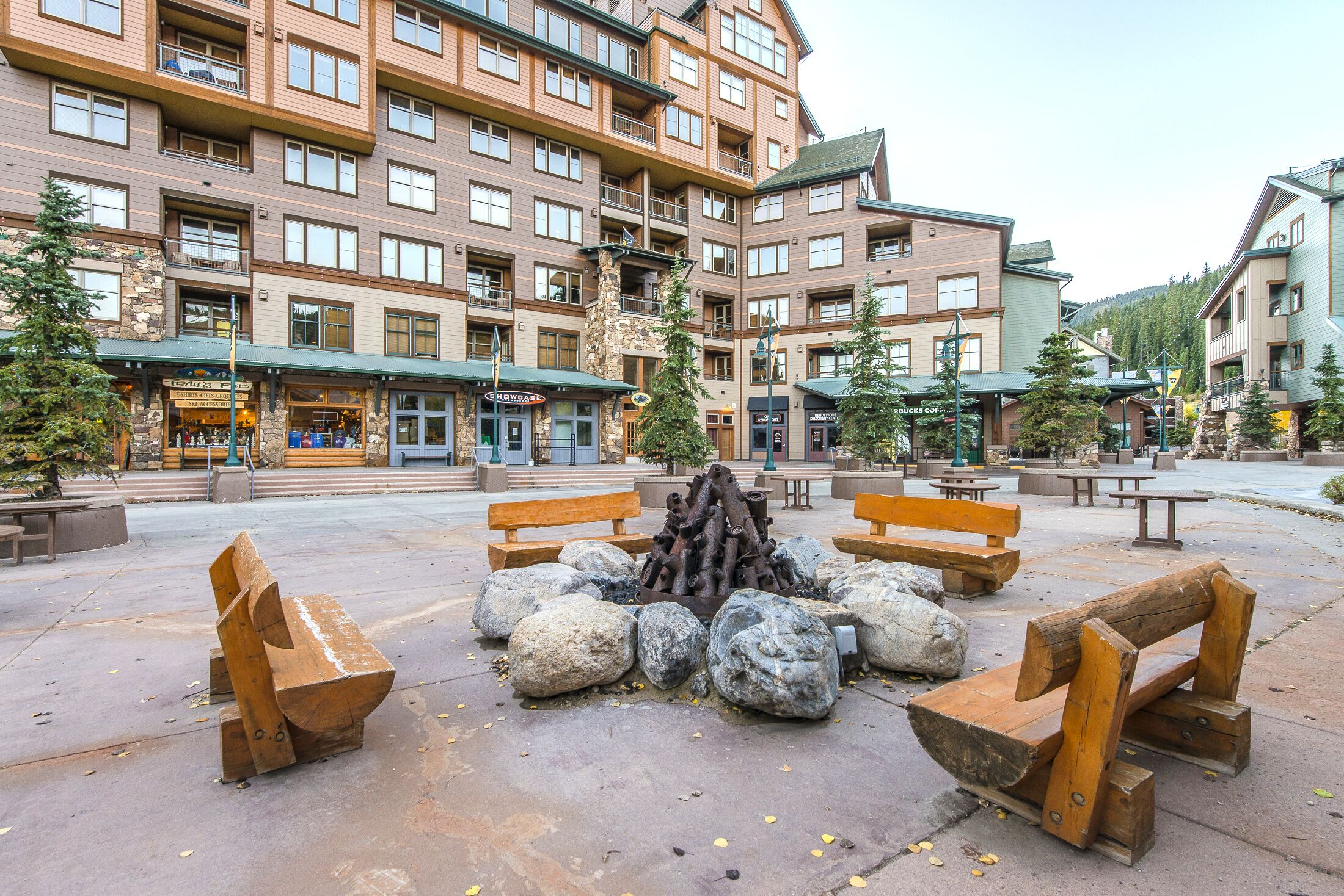 A hotel courtyard with outdoor seating, a fire pit, and a stone building with multiple windows and balconies.
