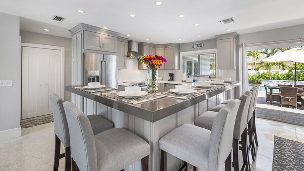 A modern kitchen with a central island, bar stools, and a view of an outdoor pool area. - SPECIALS!! BEAUTIFUL BEACH HOUSE ! WALK 2 BEACH POOL ! HOT TUB (Lauderdale-By-The-Sea)