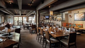 A restaurant with multiple dining tables, chairs, a bar area, and a large window providing a view of the outdoors. - 🌲Timberline D2B Premier 1-Bedroom ~Hot Tub~Pool~WiFi~Ski-in/out~Local Shuttle🌲 (Snowmass Village)