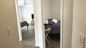 Un dormitorio con cama, mesita de noche, lámpara y ventilador de techo.